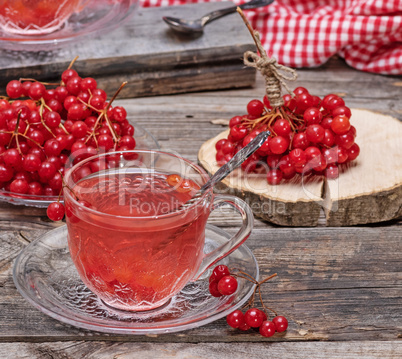 hot viburnum tea in a transparent cup with a handle and saucer