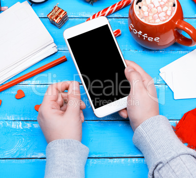 female hand holding white smart phone with blank black screen