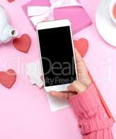 female hand holding white smart phone with blank black screen