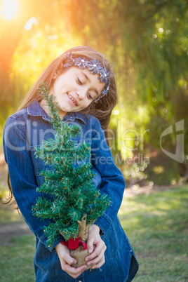 Cute Mixed Race Young Girl Holding Small Christmas Tree Outdoors