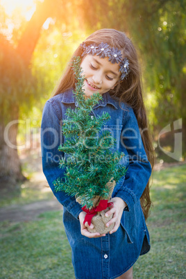 Cute Mixed Race Young Girl Holding Small Christmas Tree Outdoors