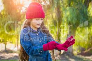 Cute Mixed Race Young Girl Wearing Red Knit Cap Putting On Mitten