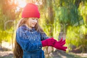 Cute Mixed Race Young Girl Wearing Red Knit Cap Putting On Mitten