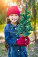 Cute Mixed Race Girl in Red Cap and Mittens Holds Tiny Tree