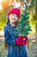 Cute Mixed Race Young Girl in Red Cap and Mittens Holds Tiny Tree