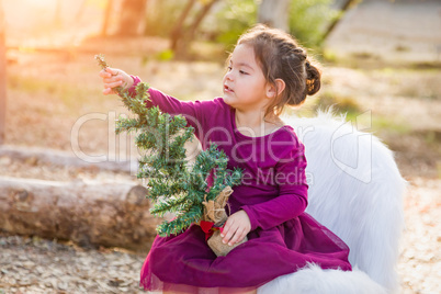 Cute Mixed Race Young Baby Girl Holding Small Christmas Tree