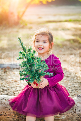 Mixed Race Toddler Girl in Santa Holding a Tiny Christmas Tree