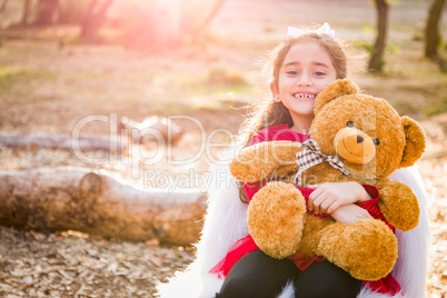 Cute Young Mixed Race Girl Hugging Teddy Bear Outdoors