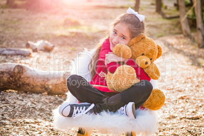 Cute Young Mixed Race Girl Hugging Teddy Bear Outdoors