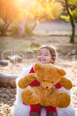 Cute Young Mixed Race Baby Girl Hugging Teddy Bear Outdoors