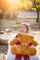 Cute Young Mixed Race Baby Girl Hugging Teddy Bear Outdoors