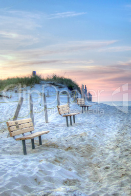 Benches line the dunes at Mayflower Beach at sunset in Dennis, C