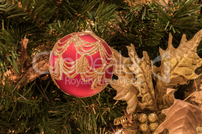 Red ornament on a Christmas tree with white lights and bows