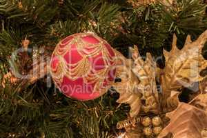 Red ornament on a Christmas tree with white lights and bows