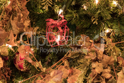 Red ornament on a Christmas tree with white lights and bows