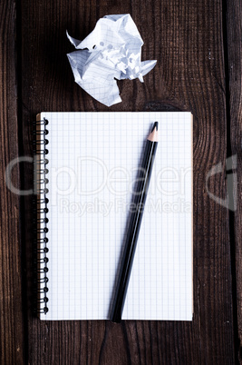 open notebook in a cell and a black wooden pencil