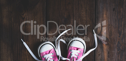small pink textile sneakers on a brown wooden background