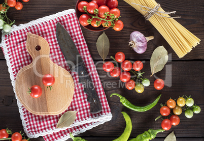 wooden cutting board with a knife and fresh red cherry tomatoes