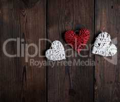 three wicker small hearts on a brown wooden background