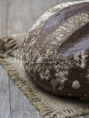 Round loaf of freshly backed sourdough bread on wooden backgroun