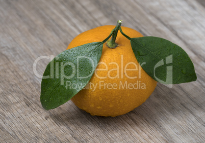 Fresh ripe tangerine with leaves on a wooden background.