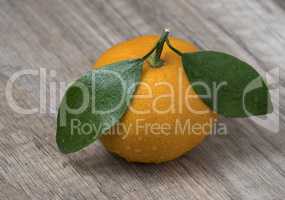 Fresh ripe tangerine with leaves on a wooden background.