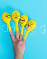 yellow balloons with faces placed on the fingers of the hand