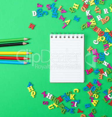 notebook with empty white sheets and multicolored wooden pencils