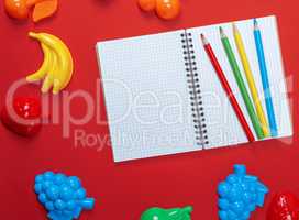 open notebook with empty white sheets and multicolored wooden pe