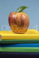 Apple fruit on top of a book stack, on the back of school classes.