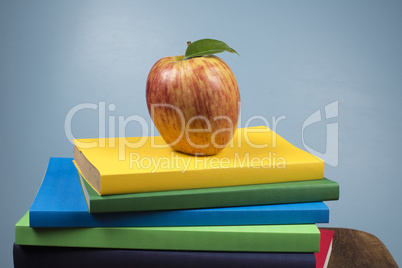 Apple fruit on top of a book stack, on the back of school classes.