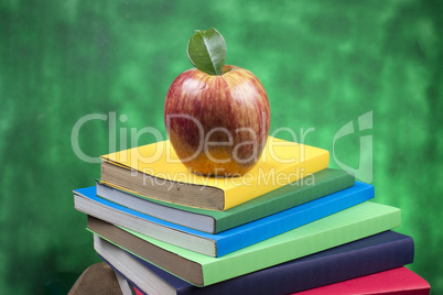 Apple fruit on top of a book stack, on the back of school classes.