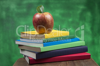 Apple fruit on top of a book stack, on the back of school classes.