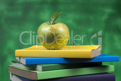 Apple fruit on top of a book stack, on the back of school classes.