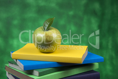 Apple fruit on top of a book stack, on the back of school classes.