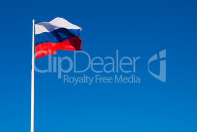 The national flag of Russia on the flagpole fluttering wind against the blue sky. Russia