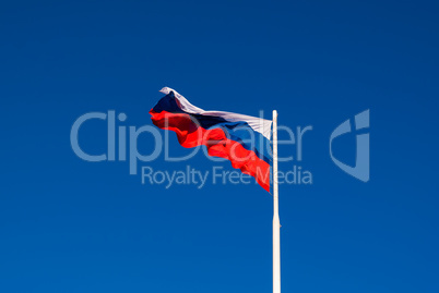 The national flag of Russia on the flagpole fluttering wind against the blue sky. Russia