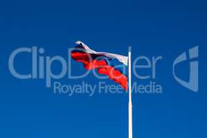 The national flag of Russia on the flagpole fluttering wind against the blue sky. Russia