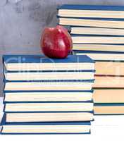 ripe red apple on a stack of books