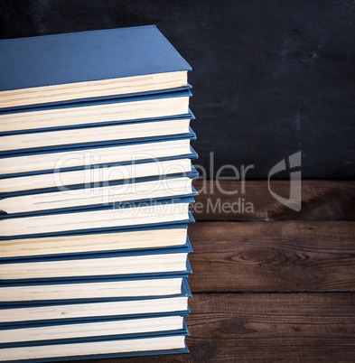 stack of books in a blue cover on a brown wooden table