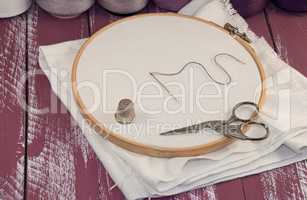 White fabric in the wooden embroidery frame with a set of thread