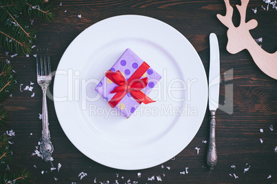 Packed gift on white empty plate, brown vintage in a festive tab
