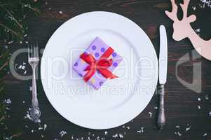 Packed gift on white empty plate, brown vintage in a festive tab