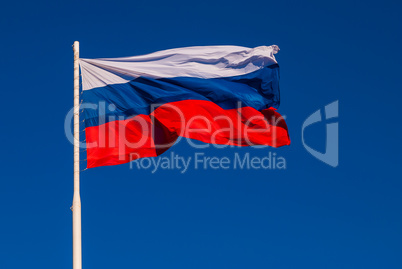 The national flag of Russia on the flagpole fluttering wind against the blue sky. Russia