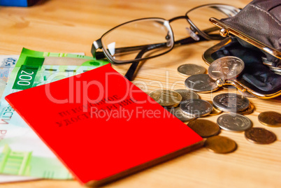 Small bills and coins, an open purse and glasses next to the pensioner's certificate are on the table