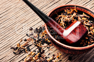 Pipe and tobacco on rustic background