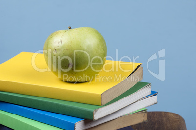 Apple fruit on top of a book stack, on the back of school classes.