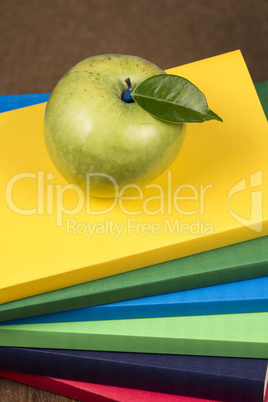 Apple fruit on top of a book stack, on the back of school classes.