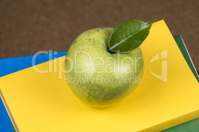 Apple fruit on top of a book stack, on the back of school classes.