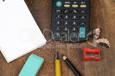 Notebook with a calculator and some pencils on a bench and green background